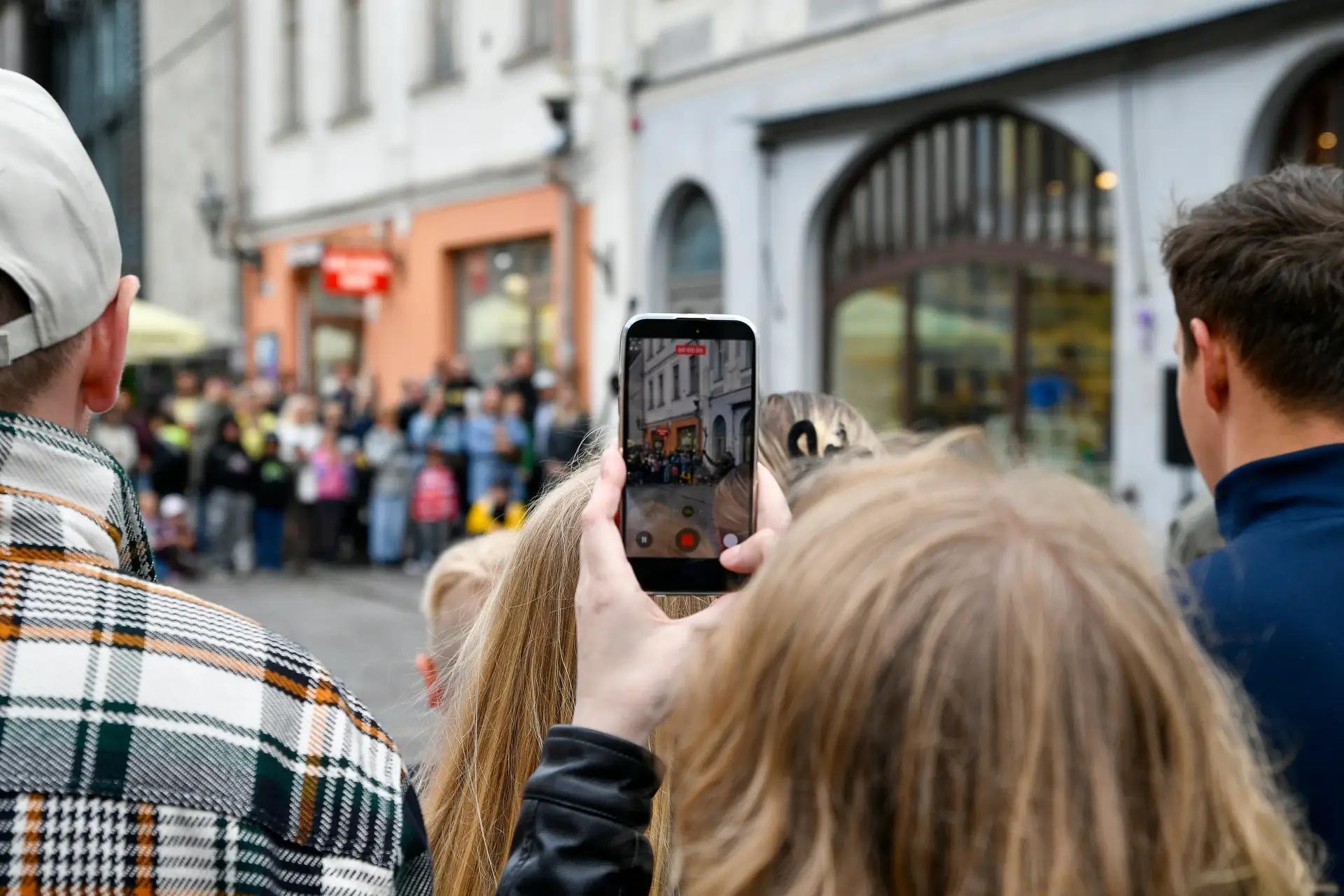 Person hält Smartphone mit geöffneter Übersetzungs-App auf Reisen, im Hintergrund fremdsprachige Schilder
