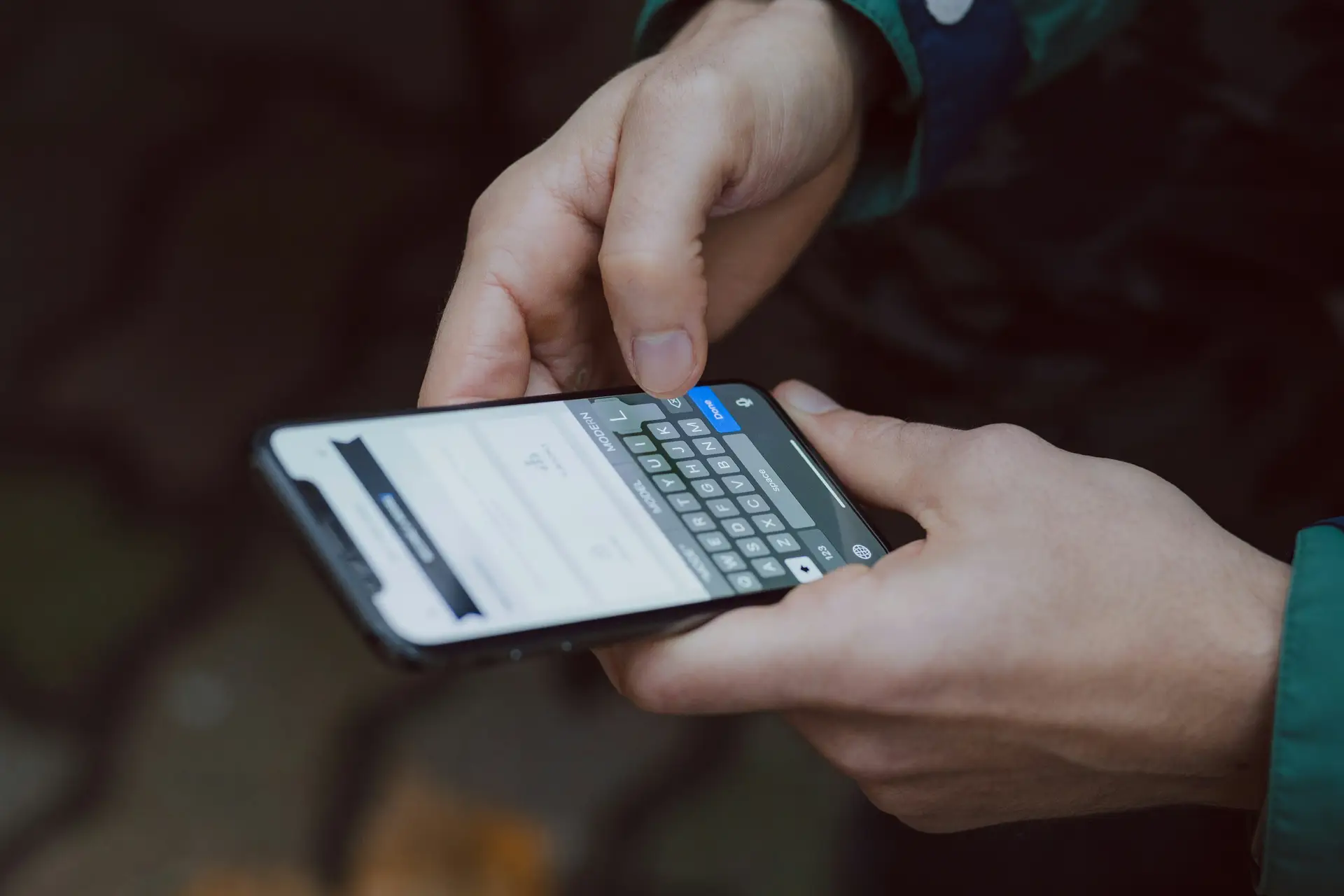 Person hält Smartphone mit geöffnetem Messenger-Chat und Sprachnachricht-Wellenform in der Hand